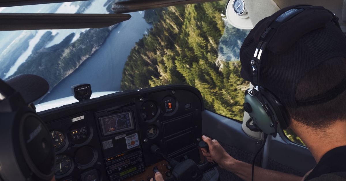 Two pilots flying over a scenic river landscape, viewed from a cockpit.